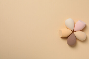 Cosmetic sponges on beige background, space for text