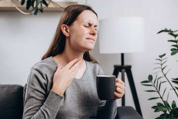 Unhealthy sad young girl touch neck hard to swallow having discomfort or painful feeling, unwell...