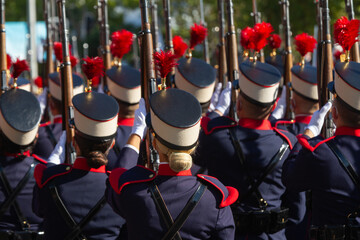 Vista de una formación de soldados con dos mujeres en uniforme antiguo durante un desfile. - obrazy, fototapety, plakaty