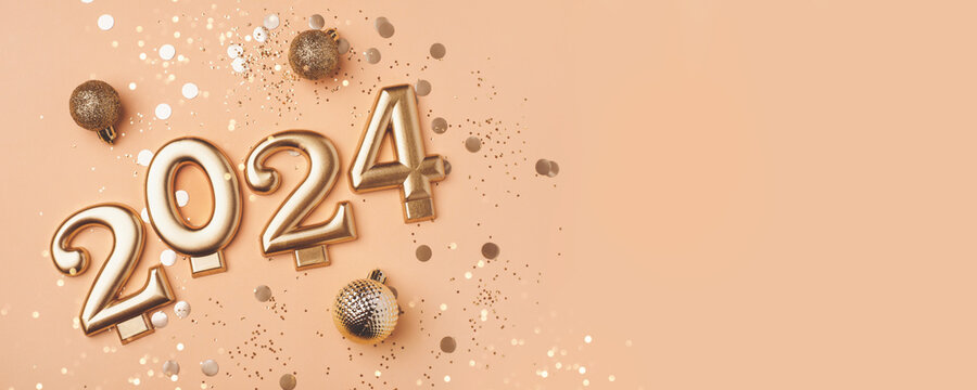 Golden 2024 on a peach color background with confetti and bokeh lights. Happy New Year 2024 is coming concept. Top view.