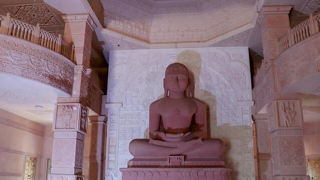 isolated red stone jain god holy statue in meditation from different angle video is taken at Shri Digamber Jain Gyanoday Tirth Kshetra, Nareli Jain Mandir, Ajmer, Rajasthan, India.