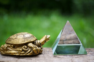 A metal turtle figurine and a glass pyramid. Esotericism and feng shui. Talismans and amulets.