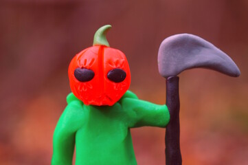 A ghost figurine with a red pumpkin and a scythe.