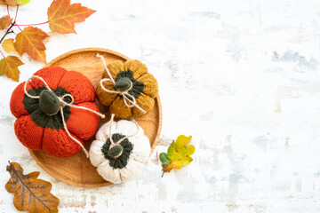 Autumn table decorations. Craft knitted pumpkins on white. Flat lay. Autumn cozy decorations.