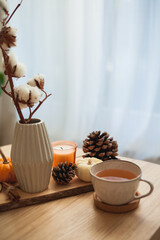 Autumn decor. Hot drink. Mug of tea, book, pumpkin, candle on a wooden coffee table. Autumn.