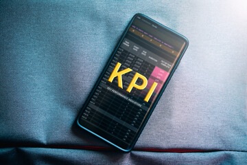 Top view photo of smartphone with KPI interface on screen and copy space. Key Performance Indicator business technology concept.