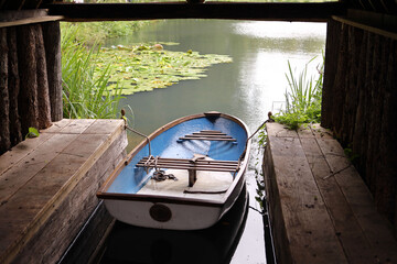 Little blue fishing boat in the shelter near the lake.