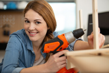woman with a drill on the factory assembling furniture