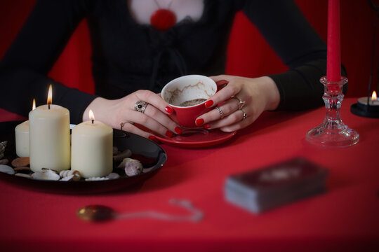  young girl in a black dress is engaged in fortune telling on coffee grounds on red background
