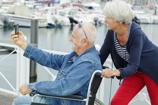 senior couple in wheelchair taking a selfie - Powered by Adobe