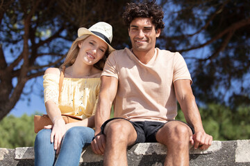 young couple at the seaside sitting on a cement wall