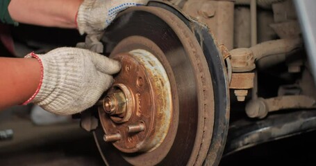 Repairing brake discs on a car with your own hands in the garage. A man is repairing his car in the workshop by unscrewing the wheel bolts. Concept of a man in a garage repairing a car.