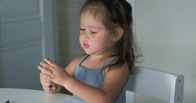 cute little girl sits on kitchen at home and draws colorful pencils, child Creation, Childhood, learning at home