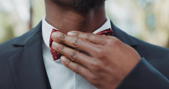 Hands, wedding and bowtie with a groom getting reading for his marriage ceremony outdoor at an event closeup. Fashion, luxury and a man dressing in a smart or formal suit for a celebration of love