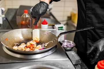 Professional chef cooking chicken curry food in wok pan on kitchen