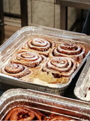 A cinnamon rolls (cinnamon bun, cinnamon swirl, cinnamon snail) with sugar icing close up. Fresh pastries in the bakery