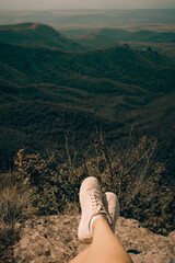 Women's legs in sneakers on top of the Kojori fortress near Tbilisi with a beautiful view of the landscape