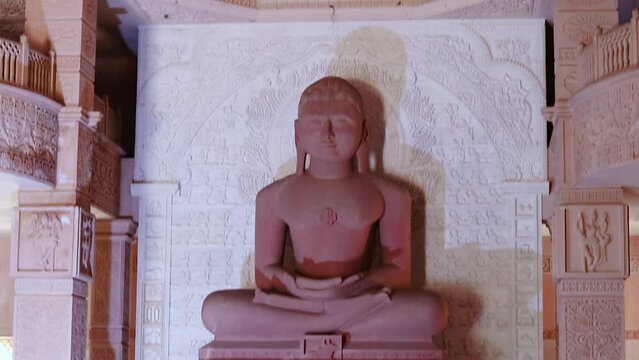 isolated red stone jain god holy statue in meditation from different angle video is taken at Shri Digamber Jain Gyanoday Tirth Kshetra, Nareli Jain Mandir, Ajmer, Rajasthan, India.