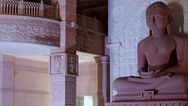isolated red stone jain god holy statue in meditation from different angle video is taken at Shri Digamber Jain Gyanoday Tirth Kshetra, Nareli Jain Mandir, Ajmer, Rajasthan, India.