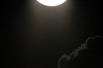 full moon photographed with a telescope and reflex camera where you can see the craters on the lunar surface, it is covered by clouds. Destination for space travel and future moon landings