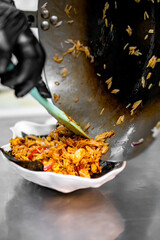 Chef cooking stir fry rice and chicken in wok pan at restaurant kitchen.