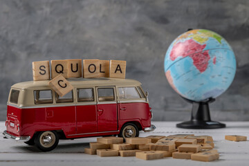 A model bus with wooden letters and a globe with the misspelled word squola which means school in...