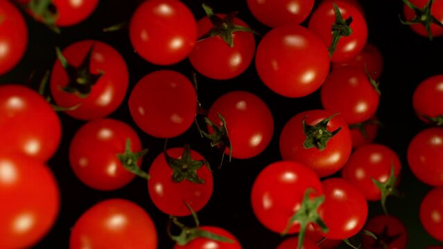 Super slow motion of cherry tomatoes flying on black background. Filmed on high speed cinema camera, 1000 fps. Camera placed on high speed cine bot, tracking the target. Speed ramp effect.