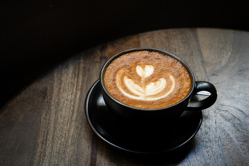 Hot coffee latte with latte art milk foam in cup mug on wood desk on top view. As breakfast In a coffee shop at the cafe,during business work concept,vintage style