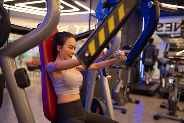 Fitness girl lifting exercising on multistation at gym for arm and shoulders muscles. Fitness...