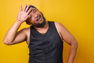 Funny tired bearded fat man in sportwear put hand on forehead on yellow background