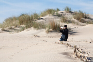 A Woman Photographing the Sky over a Beautiful Landscape with Sand Dunes. With copy space