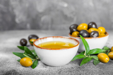 Olive oil in glass bowls, gravy boats and bottle on a textured kitchen table. Oil bottle with branches and fruits of olives. Place for text. copy space. cooking oil and salad dressing.Close-up.Flatley