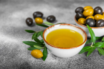 Olive oil in glass bowls, gravy boats and bottle on a textured kitchen table. Oil bottle with branches and fruits of olives. Place for text. copy space. cooking oil and salad dressing.Close-up.Flatley