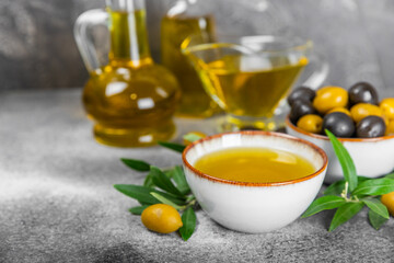 Olive oil in glass bowls, gravy boats and bottle on a textured kitchen table. Oil bottle with...