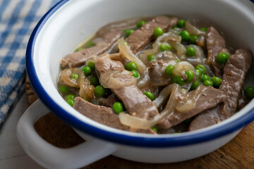 Beef strips cooked with onion and peas.