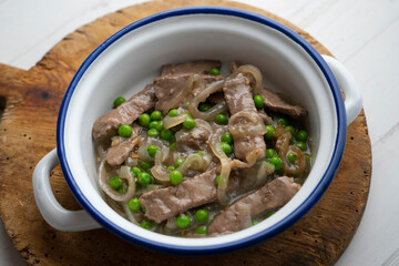 Beef strips cooked with onion and peas.