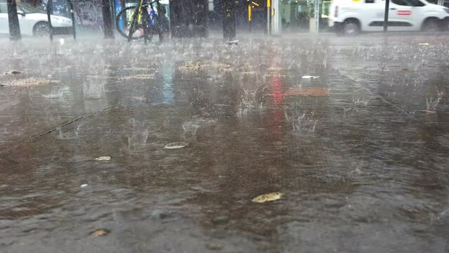 Heavy rain fall  with big rain drops bouncing of the sidewalk.