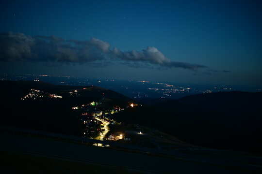 Breathtaking Evening Panorama: High Mountain Peaks Frame a Cityscape Afire with Valley Lights During the Deep Blue Hour