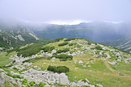 Epic Mountain Expedition: Aerial View of Mist, Lush Grass Over Peaks, and Rocky Trails Transitioning from Warm Summers to Cold Heights - Romania mountains