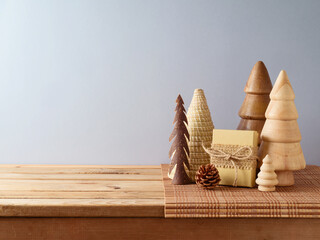 Modern sustainable Christmas decoration concept. Wooden Christmas trees on table over gray wall...