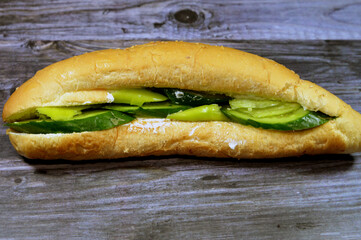 Feta white cheese with slices of fresh cucumbers and green peppers in a Long sesame bun bread, a fresh baked loaf of bread French Fino, a quick snack for breakfast and for children at school
