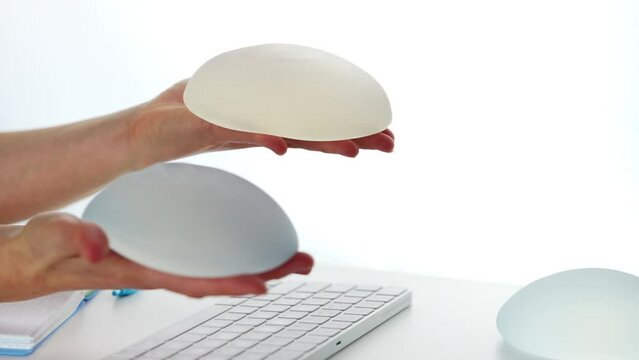 Plastic surgeon showing and squeezing soft round breast implant. Plastic surgery