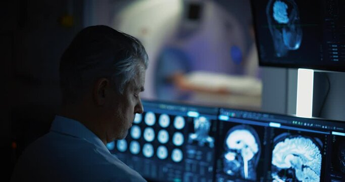 In Medical Laboratory Patient Undergoes MRI or CT Scan Process, in Control Room Doctor Watches Procedure and Monitors with Brain Scans Results. Healthcare Facility with High-Tech Equipment