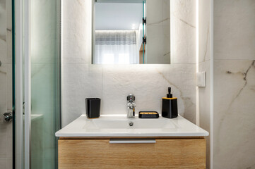 Modern bathroom with sink with wooden cabinet, mirror with light, grey colors. Interior design of hotel or apartment or home. 