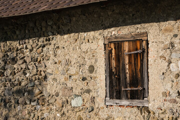 Verwitterter Fensterladen an historischer Mauer