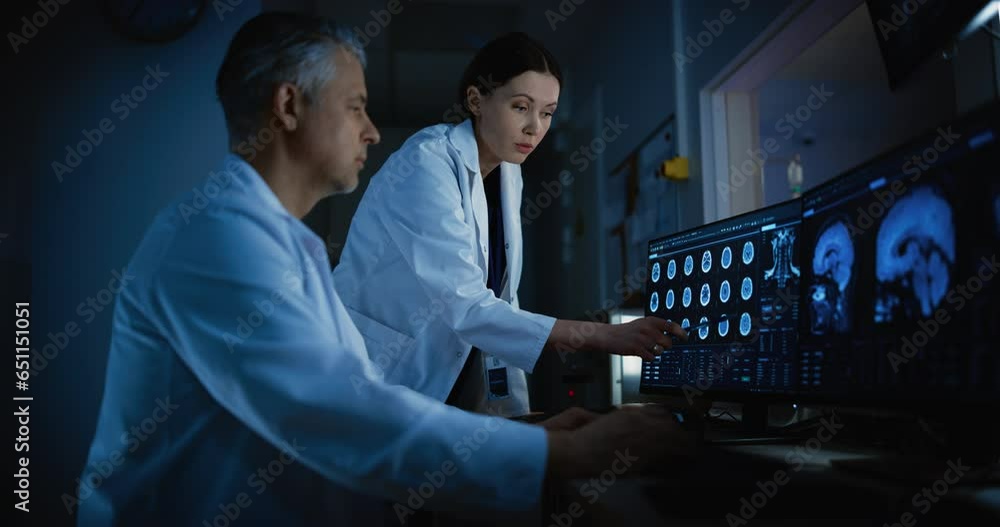 Poster in control room doctor and radiologist discuss diagnosis while watching procedure and monitors showi