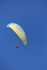 Tandem paragliding over blue sky. Yellow, white and blue color