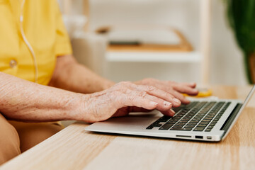 Cookie elderly woman typing on a modern laptop text close-up hands with a keyboard, online chatting.