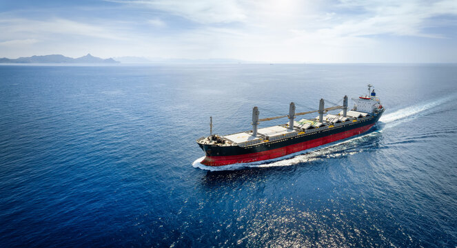 Aerial view of a bulk carrier cargo vessel traveling with high speed over blue sea with copy space as a concept for import and export industry