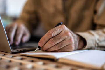 Senior man working with financial papers at home. Elderly man working on monthly expenses accounts. Finances, savings, annuity insurance and bills counting taxes - obrazy, fototapety, plakaty